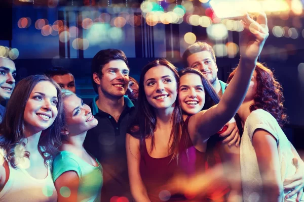 party, technology, nightlife and people concept - smiling friends with smartphone taking selfie in club