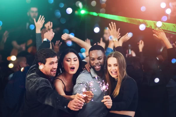 Cropped shot of a diverse group of young friends having fun with sparklers at a party at night.