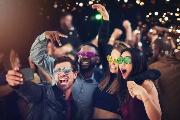 Cropped shot of a diverse group of young friends taking a selfie together at a party at night.